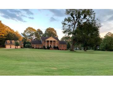 Beautiful brick home with a spacious lawn and mature trees, showcasing classic architecture and curb appeal at 130 Plantation Dr, Stockbridge, GA 30281