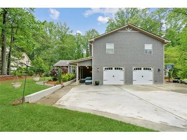 Charming two-story home with a gray shingle exterior and a two-car garage and a nice lawn at 1675 Commonwealth Trl, Cumming, GA 30041