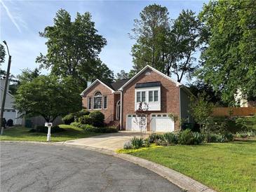 Charming brick home featuring a manicured lawn, beautiful landscaping, and a two-car garage at 504 Radford Ct, Woodstock, GA 30188