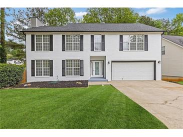 Charming two-story white brick home featuring a well-manicured lawn, attached garage, and classic curb appeal at 285 Camden Park Dr, Lawrenceville, GA 30046
