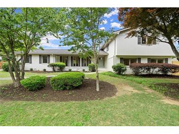 Charming white two-story home with lush landscaping and a well-manicured lawn at 1863 Trumbull Dr, Atlanta, GA 30338