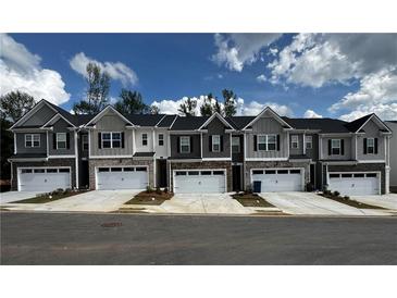 Charming two-story townhomes featuring a mix of siding and stone accents, complemented by white garage doors and well-maintained landscaping at 309 Elgin Dr # 155, Lawrenceville, GA 30045