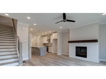 Bright living room with fireplace, modern ceiling fan, and stairs to the upper level at 1976 Deco Dr, Kennesaw, GA 30144