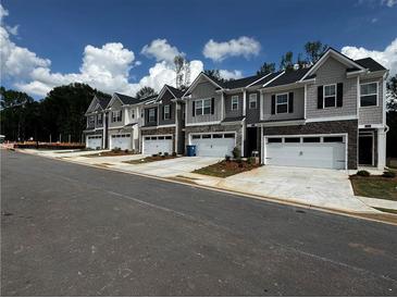 View of newly constructed townhomes featuring stone accents and attached two-car garages at 329 Elgin Dr # 157, Lawrenceville, GA 30045