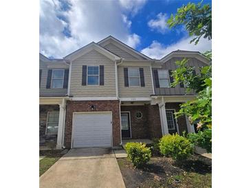 Two-story townhome featuring a brick and neutral-toned facade, attached garage, and well-maintained landscaping at 1529 Iris Walk, Jonesboro, GA 30238