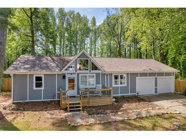 Charming home featuring a deck, two-car garage, and a welcoming front yard at 1660 Rose Garden Ln, Loganville, GA 30052