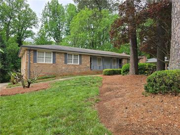 Traditional brick ranch home featuring mature trees, green lawn, and dark shutters at 1810 Trophy Dr, Marietta, GA 30062