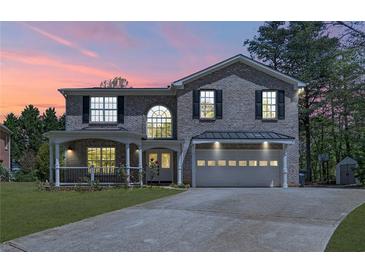 Charming two-story brick home featuring a covered porch, attached two-car garage, and well-maintained front lawn at 2055 Deans Landing Dr, Lawrenceville, GA 30043