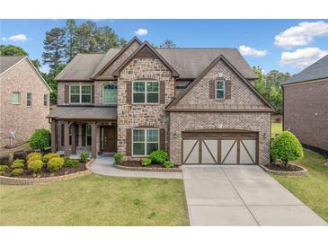 Beautiful two-story home with a brick and stone facade, manicured lawn, and two-car garage at 2435 Sentinel Chase Way, Cumming, GA 30041