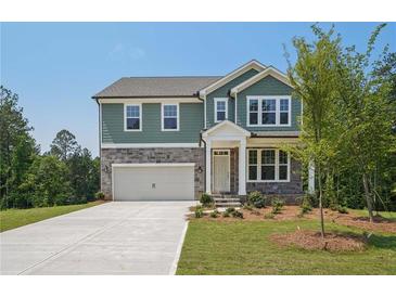 Charming two-story home featuring a stone and green-paneled facade, a two-car garage, and a well-manicured front lawn at 7252 Eton Ln, Locust Grove, GA 30248