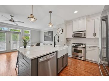 Modern kitchen featuring a large island with marble countertop, stainless steel appliances, and hardwood floors at 62 High Top Pt, Sandy Springs, GA 30328