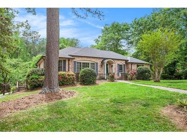 Charming brick home featuring a lush green lawn, mature trees, and colorful landscaping at 2790 Westhampton Way, Tucker, GA 30084