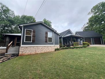 Charming home with dark siding, brick foundation, and a spacious lawn at 284 Harris Loop, Dallas, GA 30157