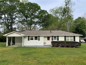 Charming single-story home with white siding, black shutters, and a covered carport nestled amongst mature trees at 66 Lakeshore Dr, Bowdon, GA 30108