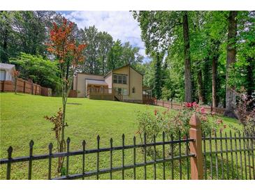 Spacious backyard featuring lush green lawn, privacy fence, and a charming two-story house at 2926 Swarthmore Dr, Lawrenceville, GA 30044