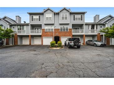 Exterior of a townhome with gray siding, brick accents, attached garages, and parking spaces at 508 Vinings Forest Se Ct, Smyrna, GA 30080