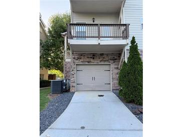 Two-car garage and driveway with balcony above in a well-maintained neighborhood at 3076 Quantum Ln, Atlanta, GA 30341