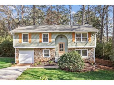 Charming split-level home with stone accents, attached garage, and well-maintained front yard at 875 Waterbrook Ct, Roswell, GA 30076