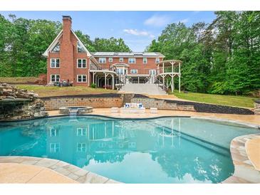 Beautiful backyard pool area with waterfall feature, gazebo, and brick house backdrop at 1212 Lee Whatley Dr, Lithonia, GA 30058