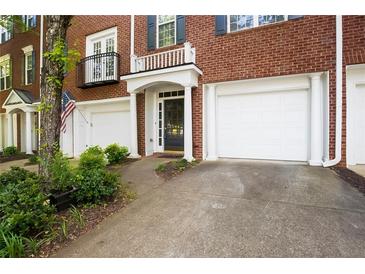 Brick townhome featuring a garage, classic architectural details, and manicured landscaping at 2108 Waters Edge Trl, Roswell, GA 30075