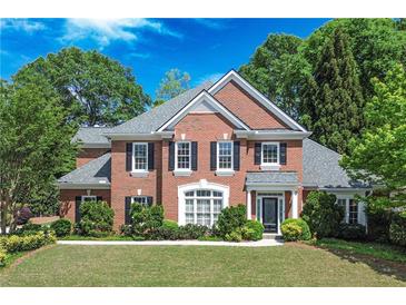 Charming two-story brick home featuring a manicured lawn and mature trees in a lovely residential setting at 9175 Etching Overlook, Johns Creek, GA 30097