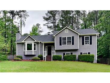 Charming gray two-story home with a well-manicured lawn and mature trees at 64 Little John Way, Douglasville, GA 30134