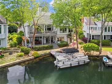 Waterfront home with a dock and a boat, featuring multiple decks and lush landscaping along the shoreline at 6330 Spinnaker Ln, Alpharetta, GA 30005
