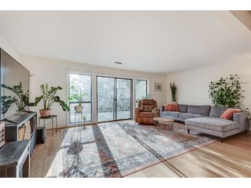 Bright living room featuring hardwood floors, a gray sectional, and sliding glass doors to the outside at 1205 Druid Knoll Ne Dr, Brookhaven, GA 30319