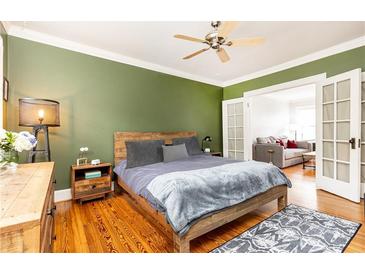 Relaxing bedroom features hardwood floors, green accent wall, wooden bed frame, and access to a living space at 1125 Briarcliff Ne Pl # 14, Atlanta, GA 30306
