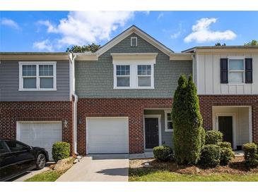 Charming townhome featuring a brick facade, attached garage, and manicured landscaping at 1881 Millstream Holw, Conyers, GA 30012