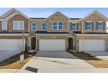 Brick townhome with a two-car garage and long driveway at 853 Pensive Run, Dacula, GA 30019