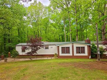 Cozy home exterior featuring well-maintained lawn and mature trees, offering a serene and private setting at 1720 Valley Ln, Cumming, GA 30040