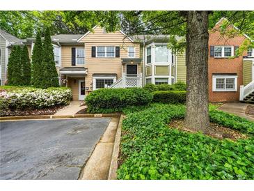Inviting two-story townhouse featuring charming curb appeal, manicured landscaping and private parking at 3019 Camden Way, Alpharetta, GA 30005