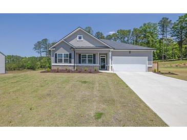 Charming single-story home featuring a two-car garage, gray siding, and a well-manicured front lawn at 707 Ralph Still Rd, Dacula, GA 30019