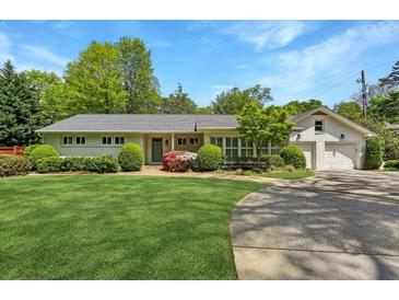 Charming home featuring manicured lawn, mature trees, and a circular driveway, creating curb appeal at 3005 Howell Mill Rd, Atlanta, GA 30327