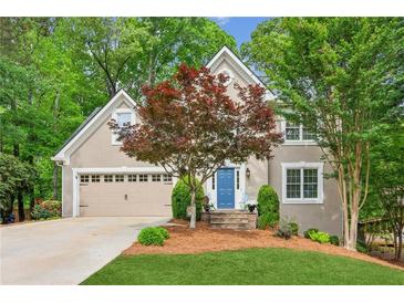 Charming exterior of home featuring a manicured lawn, blue front door, and lush landscaping at 1405 Arden Trace Ln, Lawrenceville, GA 30043