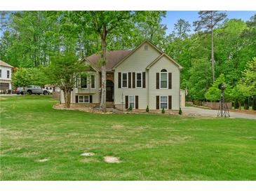 Charming two-story home with a lush green lawn, mature trees, and traditional architectural details at 3850 Pilgrim Mill Rd, Cumming, GA 30041