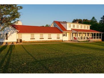 Expansive white farmhouse with a red roof, offering charm and curb appeal against a lush green lawn at 4076 Airline, Mcdonough, GA 30252