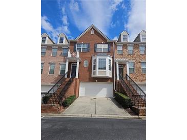 Brick townhome featuring an attached garage and well-maintained front yard landscaping at 6121 Joybrook Rd, Johns Creek, GA 30097