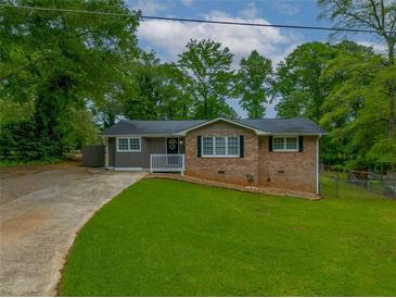 Charming single-story home featuring a brick facade, white trim, and a lush green lawn at 6892 Autumn Hills Dr, Douglasville, GA 30135