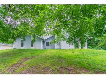 Charming home exterior with green lawn, partial view under trees at 6255 Saddlewood Dr, Lithonia, GA 30058