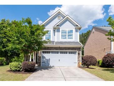 Charming two-story home featuring blue siding, stone accents, an attached garage, and a well-manicured front yard at 2341 Lily Valley Dr, Lawrenceville, GA 30045