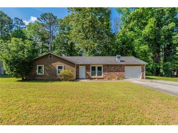 Charming single-story home features a brick facade, an attached garage, and a well-maintained lawn at 5326 Rocky Pine Dr, Lithonia, GA 30038