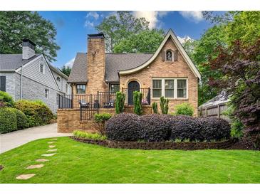 Charming brick home with a manicured lawn, garden bed, and front porch featuring black iron railings at 2580 Acorn Ne Ave, Atlanta, GA 30305
