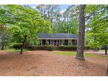 Charming brick home featuring a cozy front porch surrounded by lush, mature trees in a picturesque setting at 681 Hampton Sw Pl, Marietta, GA 30064