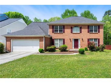Charming brick home featuring well-manicured lawn, dark shutters, and an attached two-car garage at 930 Palmer Rd, Lithonia, GA 30058