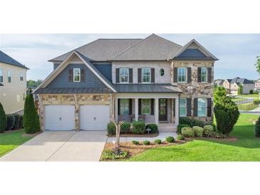 Charming two-story home showcasing a stone and siding facade with a well-manicured lawn and a two car garage at 4280 Castlewood Rd, Cumming, GA 30040