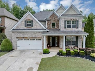 Beautiful brick home featuring a manicured lawn and inviting front porch perfect for relaxing at 2376 Roberts View Trail, Buford, GA 30519