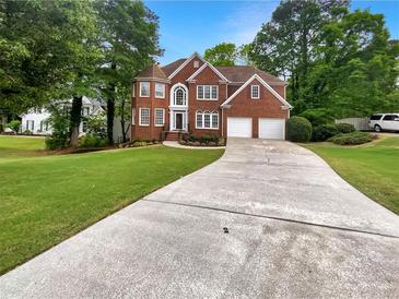 Traditional brick home with a two-car garage, well-manicured lawn, and a long driveway on a sunny day at 9979 Bridgewater Pointe, Villa Rica, GA 30180