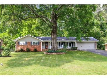 Charming one-story home featuring a brick facade, well-manicured lawn, and a beautiful mature tree at 1732 Samaria Trl, Tucker, GA 30084